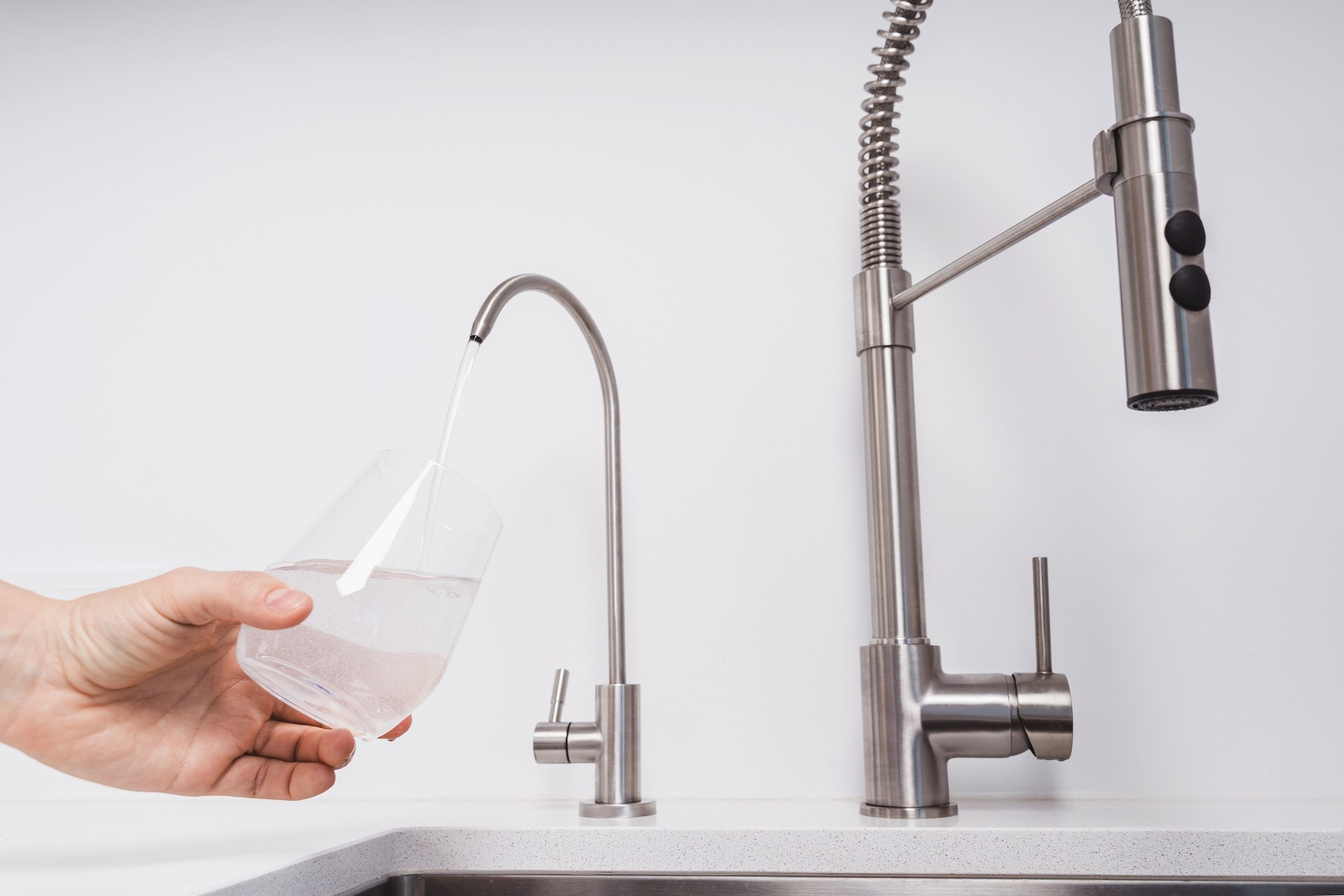 La donna ottiene acqua filtrata dal rubinetto inossidabile in un bicchiere